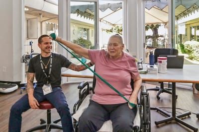 Resident participating in physical therapy with staff support