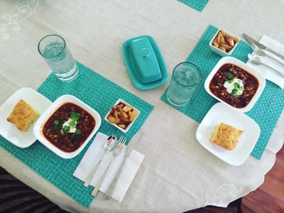 Two bowls of stew with sides on a dining table
