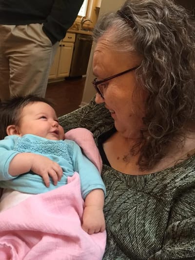 An older woman smiling at a baby in her arms