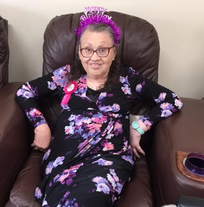 Resident celebrating with a crown and sash in a common area