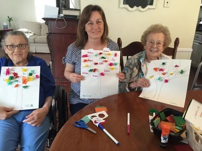 Residents and staff engaged in an art activity with trees