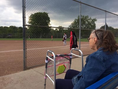 A resident watching a softball game from the sidelines