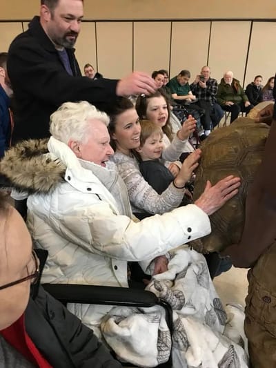 Residents and family interacting with a therapy animal in a common area