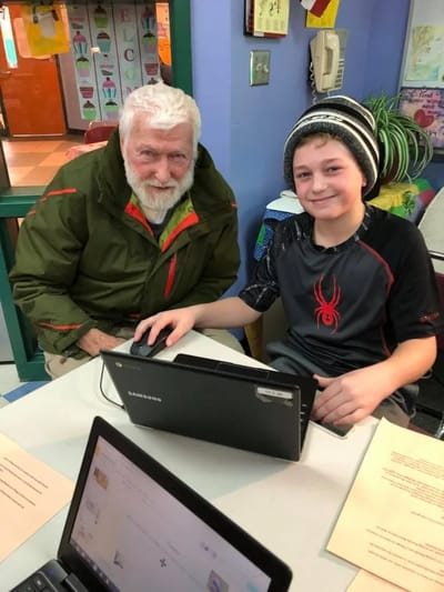 An elderly man and a young boy sharing a computer
