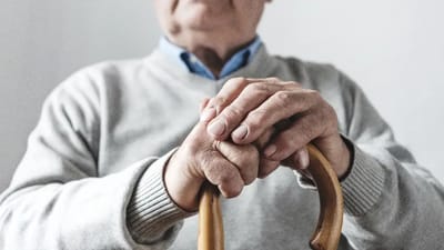 Close-up of an elderly person holding a cane