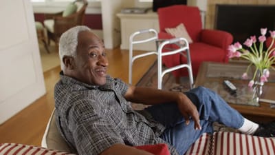 A smiling senior man sitting comfortably indoors.