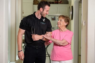 Healthcare professional assisting an elderly woman indoors.
