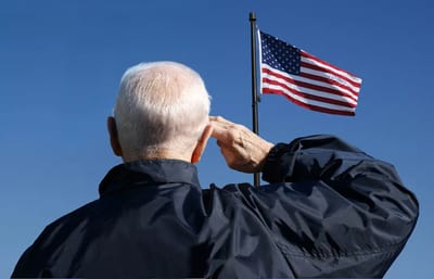 Elderly man saluting in front of an American flag