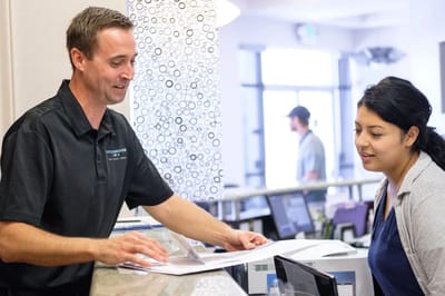 Staff member assisting a visitor at reception.