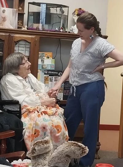 Senior resident interacting with staff member in a cozy setting.