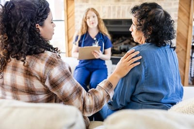 Two people comfort a resident with a caregiver present.