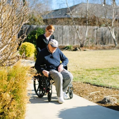 Caregiver assisting a resident in a garden pathway