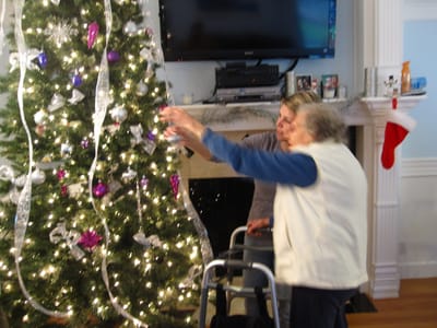 Two residents decorating a Christmas tree