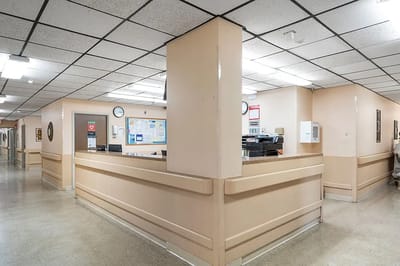 Interior view of a nursing facility hallway with desks and signage
