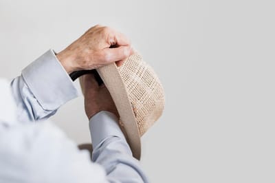 Elderly hands adjusting a straw hat