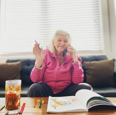 Senior woman coloring while talking on the phone.