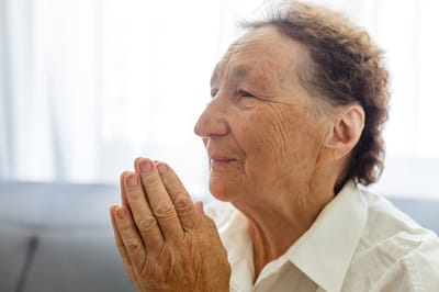 Close-up of a resident with hands clasped in thought