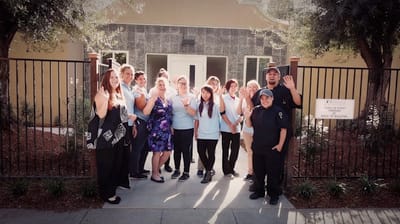 Staff members waving in front of the facility entrance