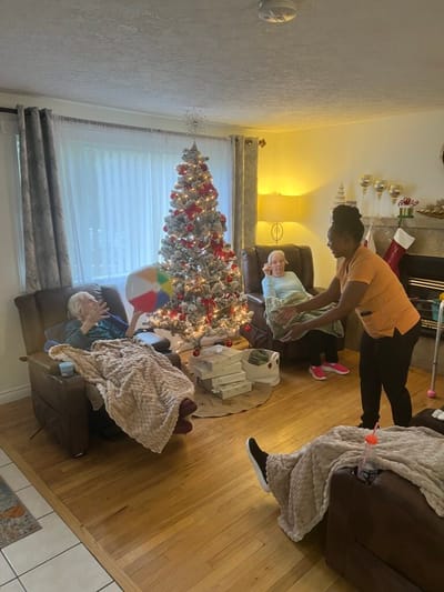 Residents celebrating by a Christmas tree in a cozy lounge