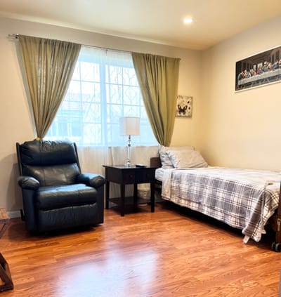A cozy interior of a resident's room with a chair and bed