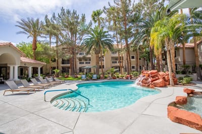 Swimming pool surrounded by palm trees and lounge chairs