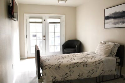 A private resident room with bed and balcony doors