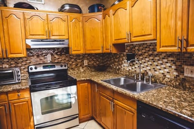 Brightly lit kitchen with wooden cabinets and granite countertops