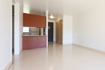 Interior view of a bright, empty room with kitchenette
