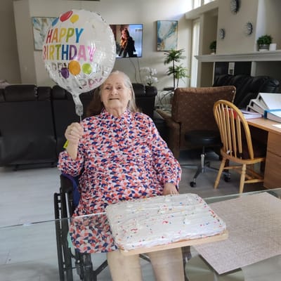 Resident celebrating birthday with cake and balloon