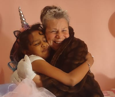 A joyful hug between a woman and a girl in costume.