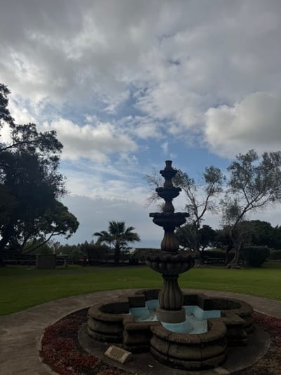 A fountain in a landscaped garden with cloudy skies