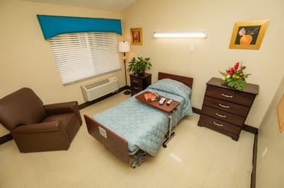 A private resident room with bed and chair