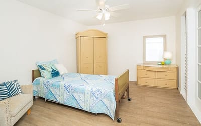 A bright resident room with a bed and dresser