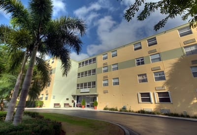Exterior view of Puerta Del Sol facility with palm trees