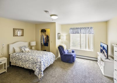 A well-furnished private resident room with a bed and recliner