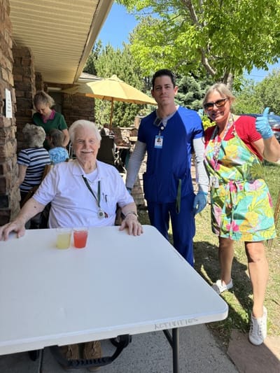 Residents enjoying refreshments outdoors with staff