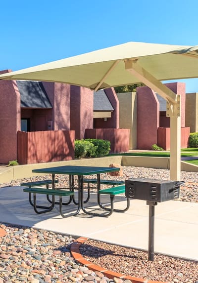 Outdoor picnic area with shaded table and surrounding buildings