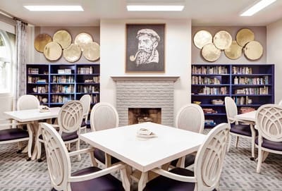 A cozy common area with bookshelves and tables
