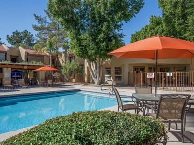 Outdoor pool area with shaded seating and greenery