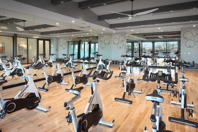 A fitness room with stationary bikes and large windows