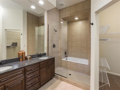 Modern bathroom with double vanity and glass shower.