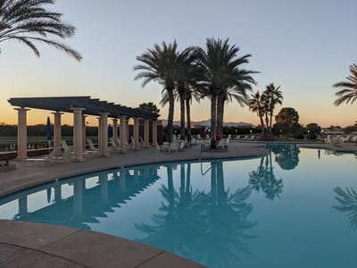Outdoor pool area surrounded by palm trees at sunset