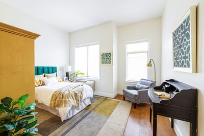 A well-decorated resident room with a bed and armchair