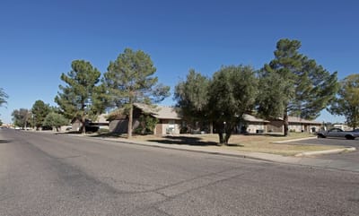 Exterior view of Kachina Apartments with trees and street