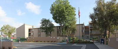 Exterior view of the Del Amo Gardens building with trees and parking