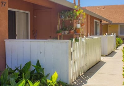 Outdoor view of resident apartments with plants and a white fence