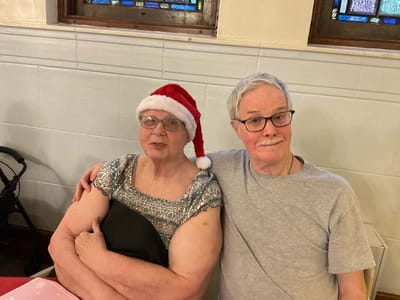 Two residents sharing a moment, one in a Santa hat