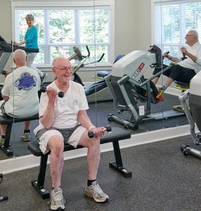 Residents exercising in a fitness room with equipment