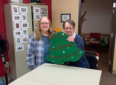 Two residents proudly display a handmade Christmas tree decoration