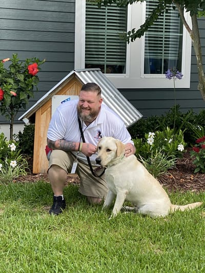 A staff member with a dog in a garden area